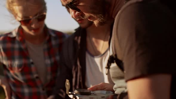 Bearded Spectacled Caucasian Male Holding Map and Compass Surrounded By Two Friends Trying to Find alt