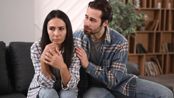 Candid Caucasian Young Man Consoling His Upset Wife or Girlfriend While Sitting on Couch at Home in alt