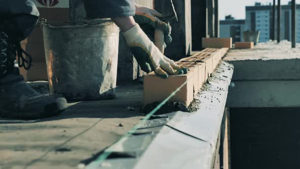 Bricklayer Works on Construction Site alt