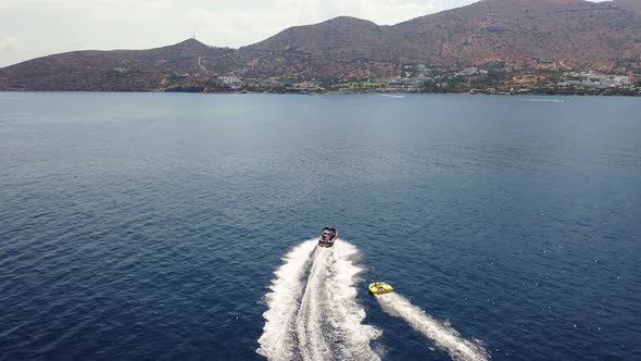 Aerial View of a Motor Boat Towing a Tube. Elounda, Crete, Greece