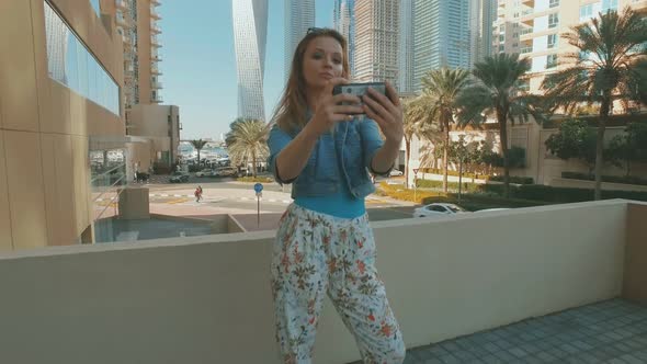 Caucasian Woman Is Taking Selfies By Smartphone, Outdoors in Dubai Marina in Sunny Day