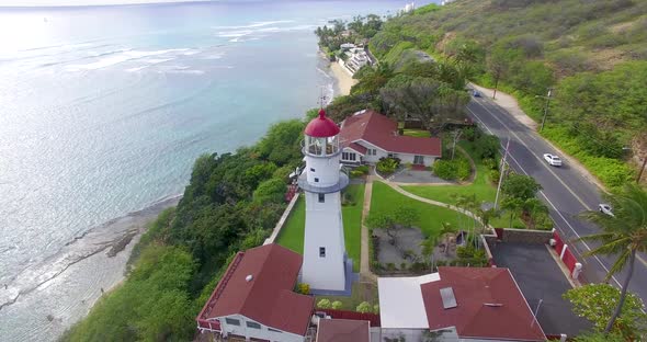 Circling aerial shot of a lighthouse on a cliff near the ocean in Hawaii alt