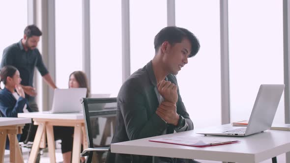 A young company employee is feeling tired while sitting at work for a long time. alt