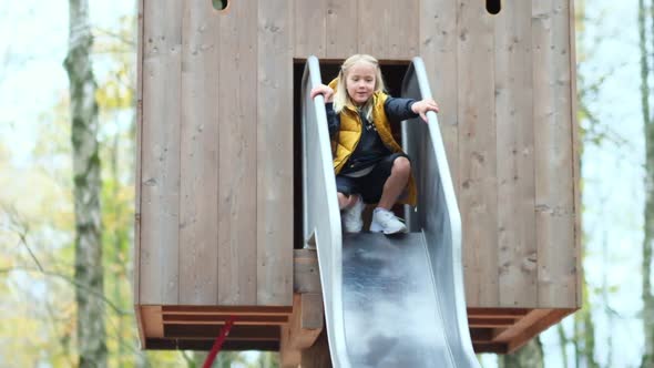 Cute Cheerful Girl at the Entrance To the Tree House Is Dancing Going To Slide Down the Hill alt