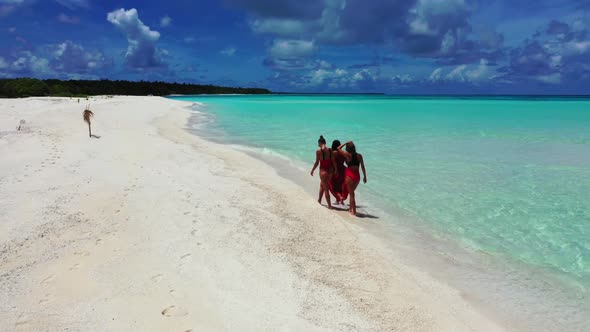 Women enjoying life on idyllic tourist beach time by shallow ocean with white sandy background of th alt