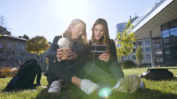 Happy Teenage Friends Using Tablet Computer Computer at Park in Centre of the Town alt