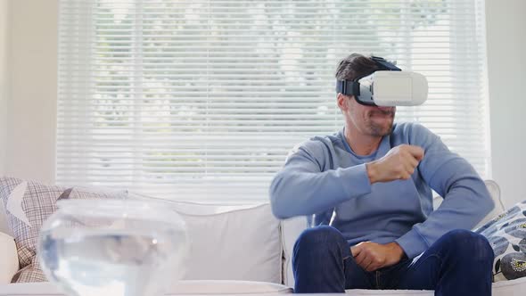 Young man sitting on sofa experiencing virtual reality headset 4K 4k alt