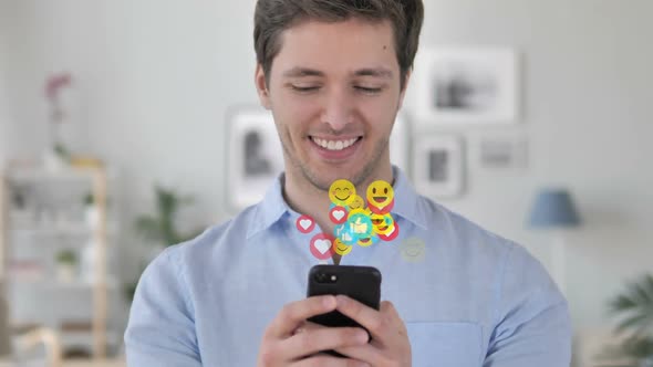 Happy Man Text Messaging on Smartphone Flying Emojis Smileys and Likes alt