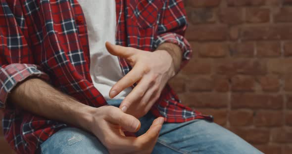 Close Up of Young Man Sitting on Chair and Talking While Gesturing Hands alt