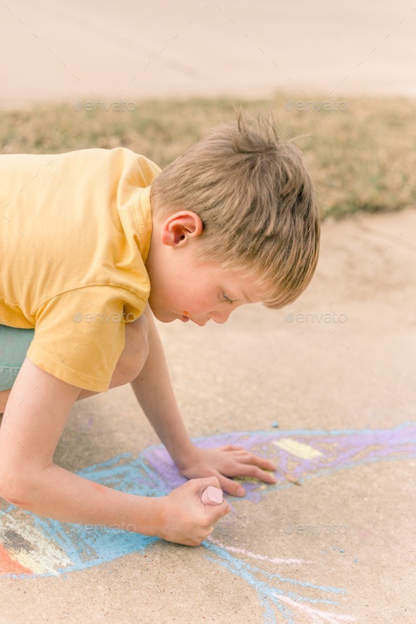 6 year old boy drawing on sidewalk with chalk