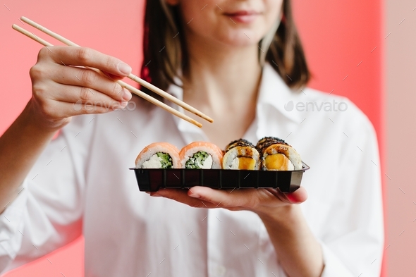 Sushi delivery service background, woman eating sushi in plastic package, no face, red light