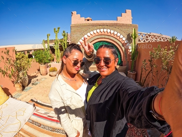 LGBTQ cute lesbian gay couple happy in a riad hotel in Marrakech Morocco, girl with braids, summer