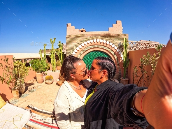 LGBTQ cute lesbian gay selfie kissing in hotel riad in Marrakech Morocco, girl with braids, summer