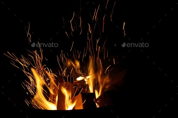 Bonfire sparkling in the black night, beautiful warm high orange flames, the heat is on - fire!!