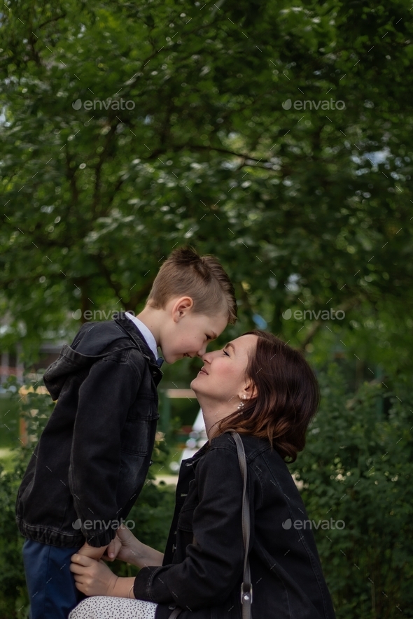 a young pretty mother gently touches her son\'s nose with her nose