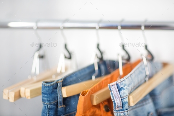 clothes bottoms jeans pants shorts on hangers in closet. concept of clothing store and organization