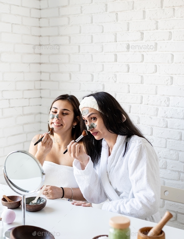two beautiful women applying facial mask having fun