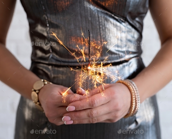 sparkler in woman’s hands. Female hands with jewelry holding sparkler