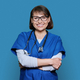 Portrait of middle aged doctor in uniform looking at camera on blue background - PhotoDune Item for Sale
