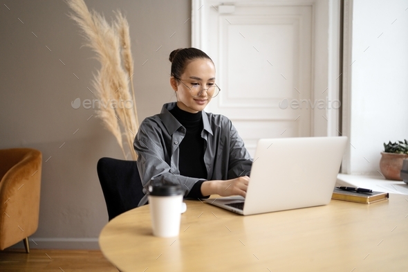woman designer freelancer in glasses works in office uses laptop computer project report