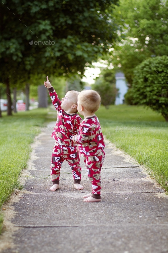 Twins outside pointing at airplanes