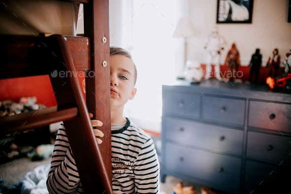 Young boy in bedroom learning summer vacation almost over sad