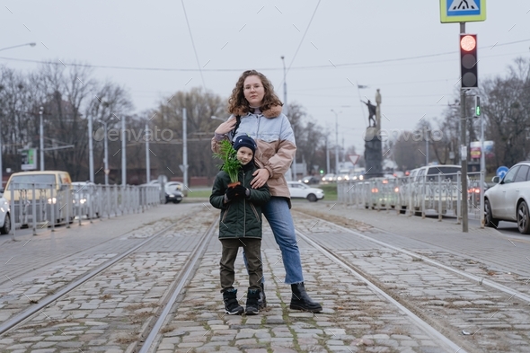 mom and son stand on the tram tracks in the middle of the road
