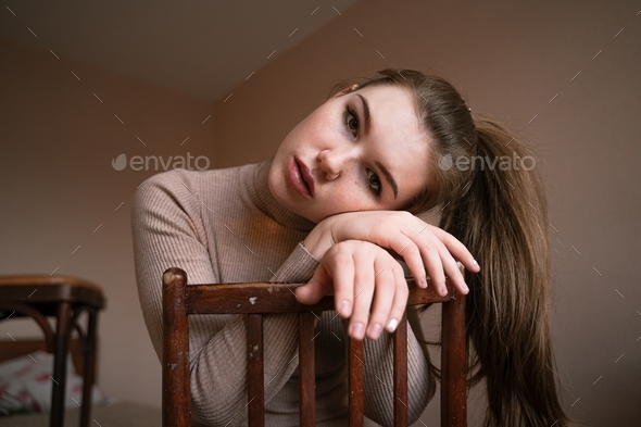 portrait of a girl with hair tied in a ponytail, put her head on the back of a chair