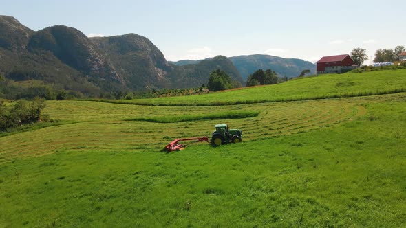 Farmers cutting green grass for hay in Rogaland, Norway -Aerial alt