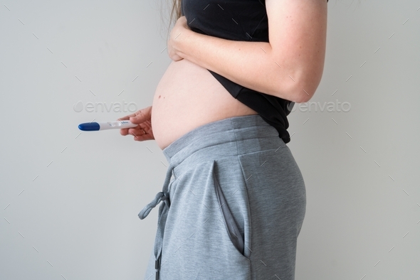 Pregnant woman shows a positive pregnancy test. Concept of happy family