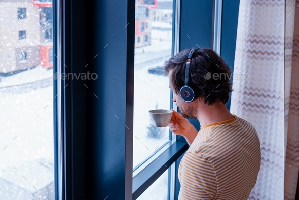 adult programmer talks to coworkers using a wireless headset and looks out the window of home office