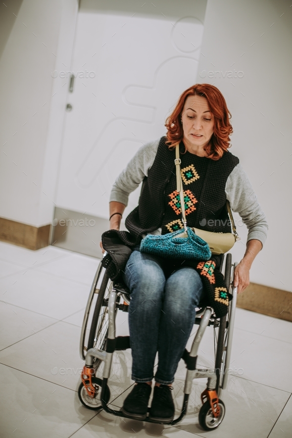  woman in a wheelchair near washroom door with a toilet sign for people with disabilities.