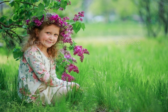 Banner little girl in a wreath sits under a lilac bush with flowers. Spring in Kyiv Ukraine