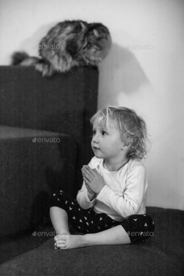 Little girl praying sitting on the floor with her hands clasped in a prayer pose