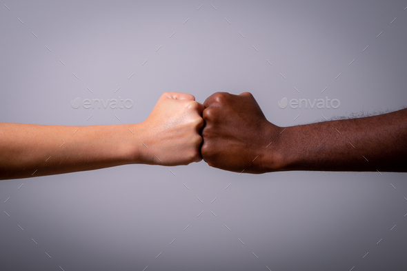 Two fists, one white and one black touching, concept of fight against racism.