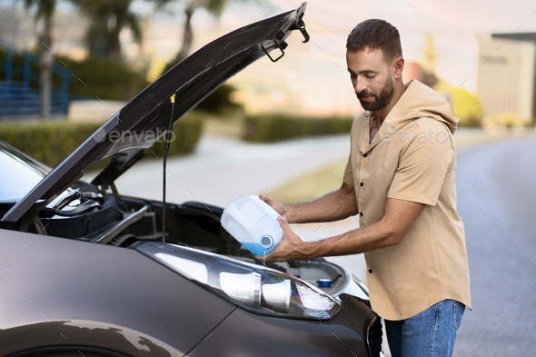 man pouring windshield washer fluid for clearing car. Car service concept