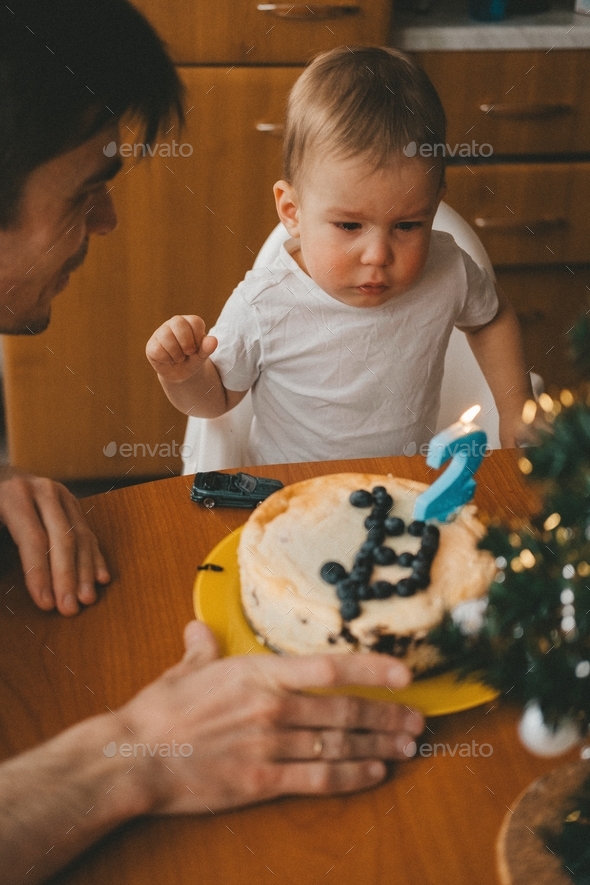 dad and son are watching a birthday cake that mom made