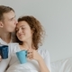handsome young couple kissed and held a coffee mug on bed - PhotoDune Item for Sale