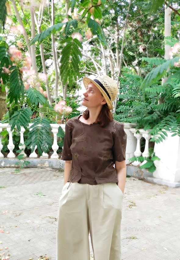 A middle-aged woman shows off a handmade felt blouse on a summer day