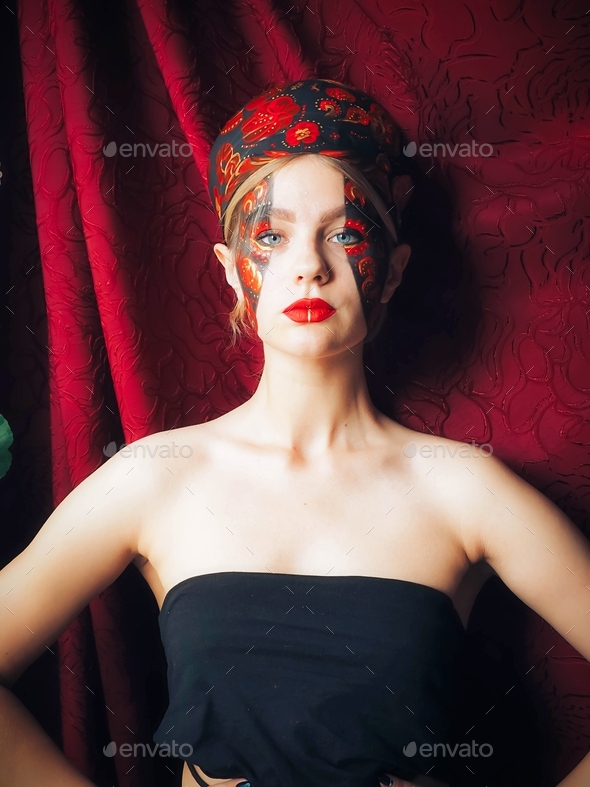 Young woman with a fantasy makeup in the style of Russian fairy tales on a dark red background