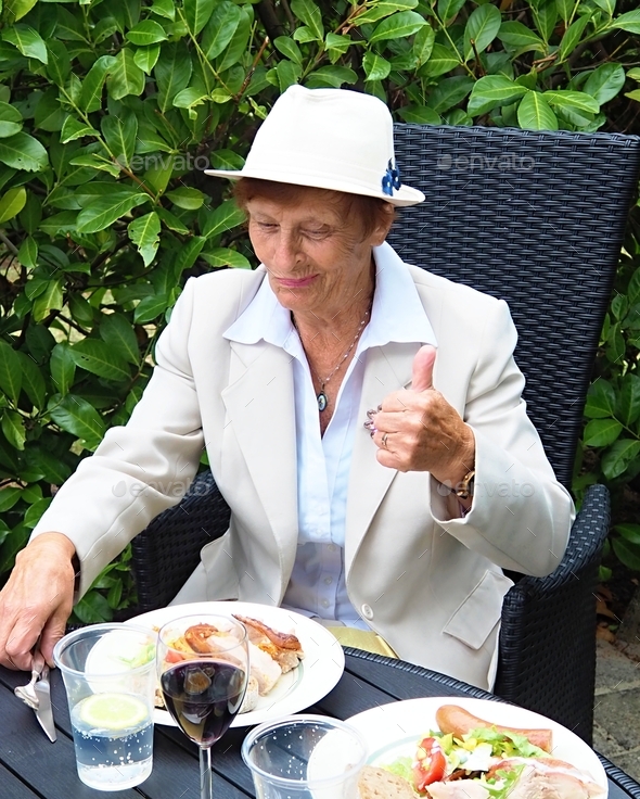 An elderly lady has lunch in an outdoor cafe  - Stock Photo - Images