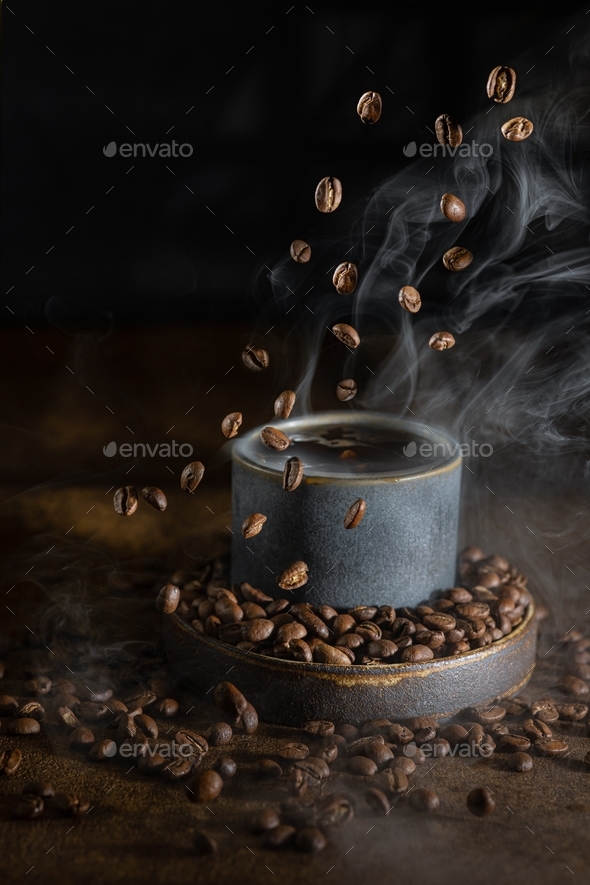 Coffee beans fly into a cup with steam