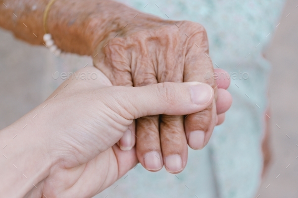 Young male man holding his grandmother hand with carefulness,family affection concept
