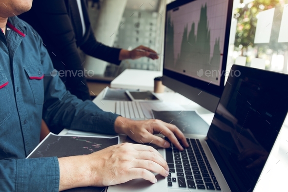Two investors work together and note the stock price to compare with other stocks. - Stock Photo - Images