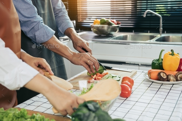 Two young asian couples are helping each other and enjoying cooking in the kitchen. - Stock Photo - Images