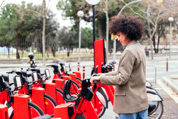 young woman taking a bike from a rental station