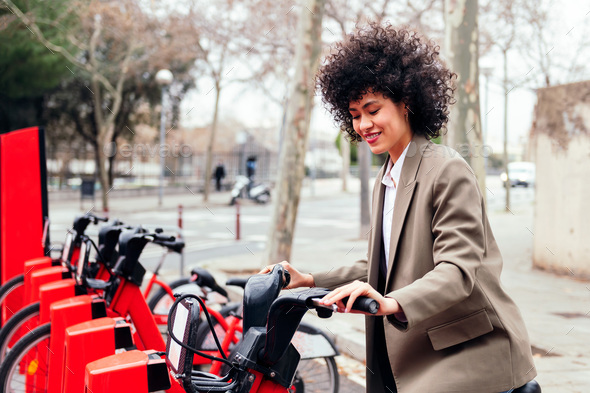 smiling woman taking a bike from rental station