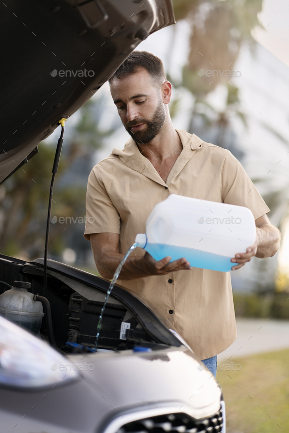 Worker pouring windshield washer fluid. Car service concept