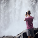 Rear view of tourist while taking pictures of waterfall - PhotoDune Item for Sale