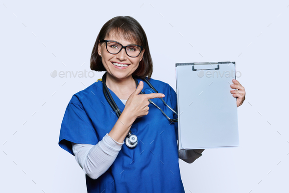 Woman doctor pointing with finger at blank paper on clipboard, white background - Stock Photo - Images